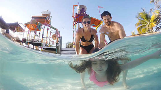 Crianças com seus pais mergulhando no Hot Beach com brinquedos aquáticos ao fundo - Blog - Hot Beach Parques & Resorts | 