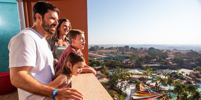 Família na sacada do resort olhando para o parque aquático