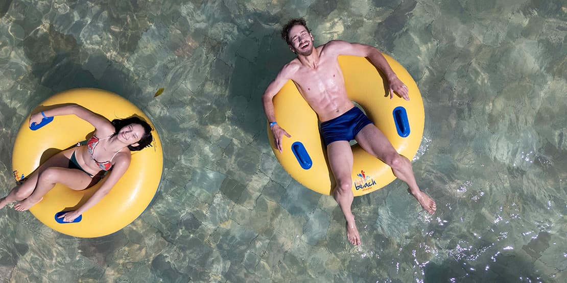 casal deitado em boias na piscina