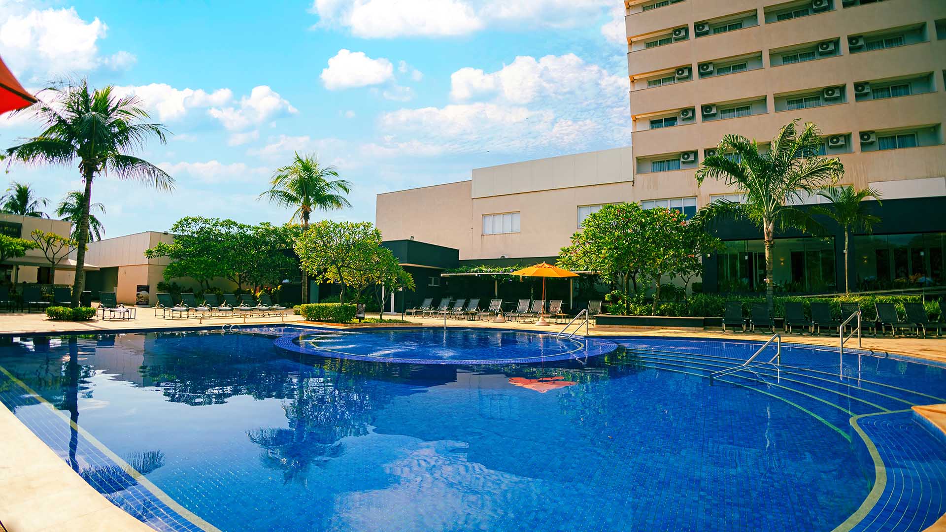 piscina grande do celebration resort olímpia, coqueiros e o prédio no horizonte com um céu claro e ensolarado